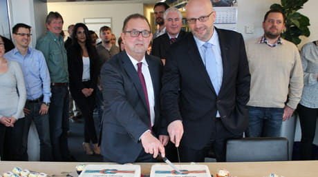 Michael Hollstein cutting office merger cake in Hamburg